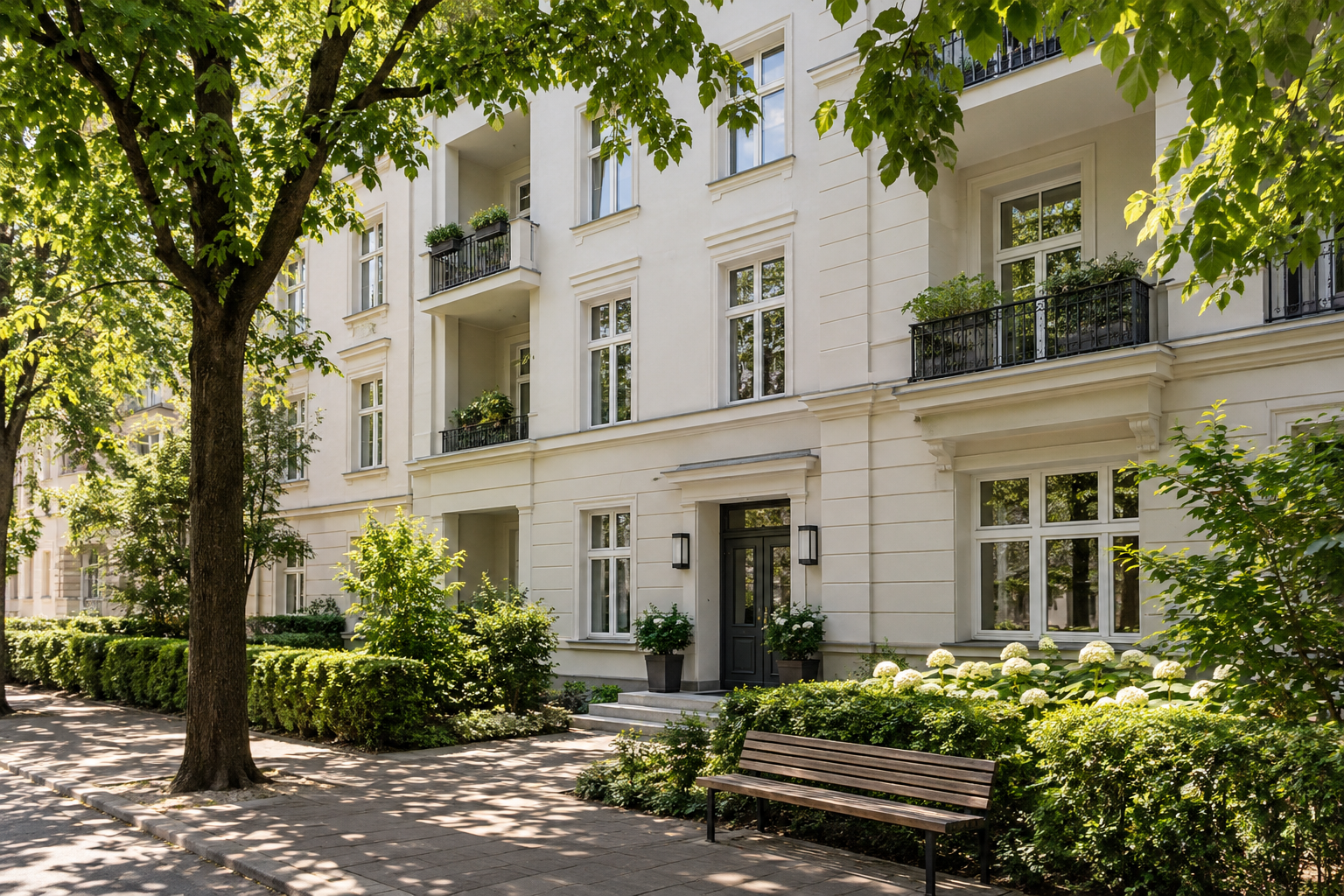 Helles Wohnhaus hinter großen Straßenbäumen